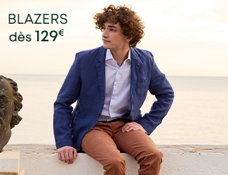 Homme portant un blazer bleu marine et un pull beige avec le texte 'Blazers dès 129€